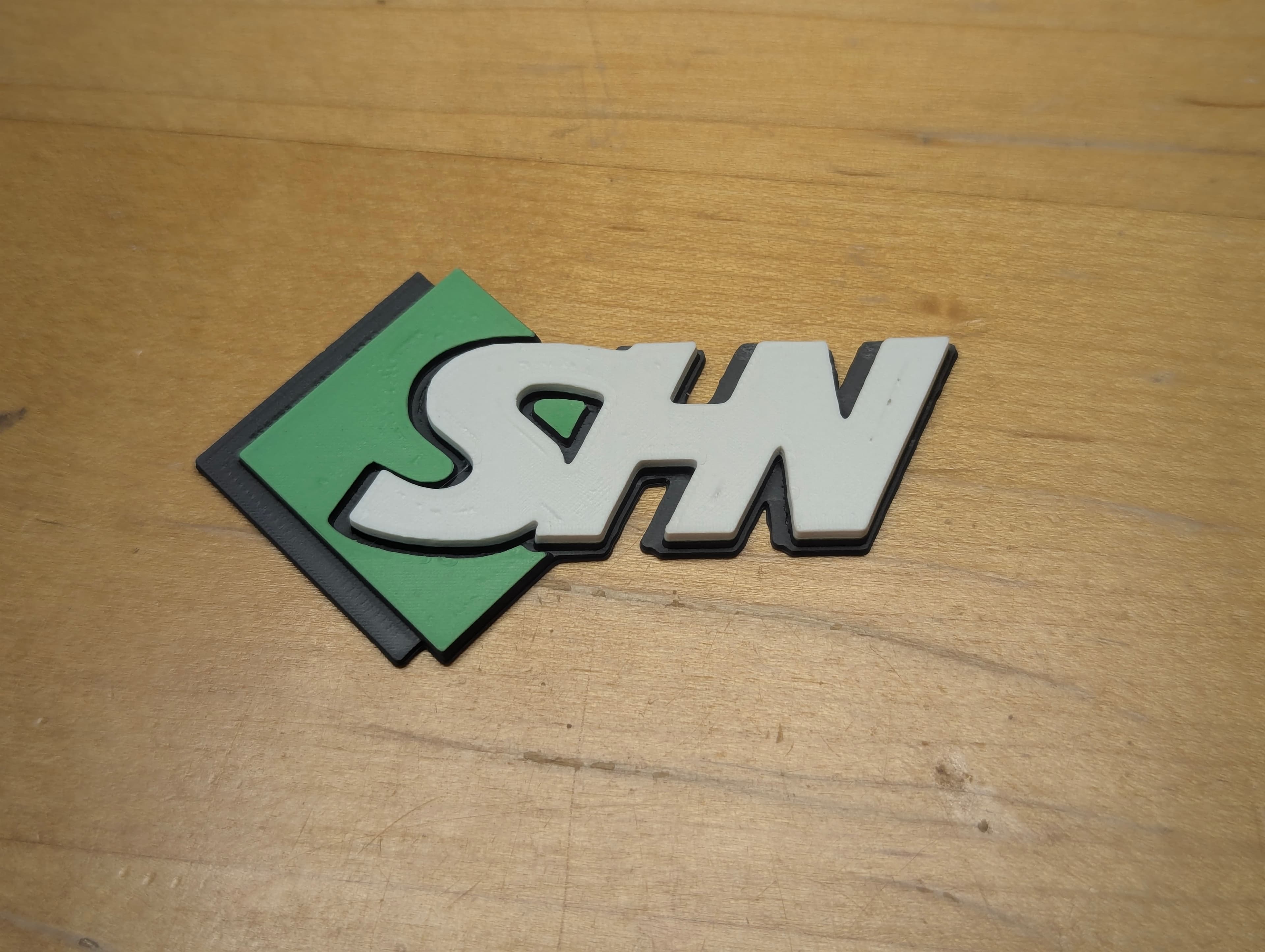 SHN logo printed in filament — green, white, and black