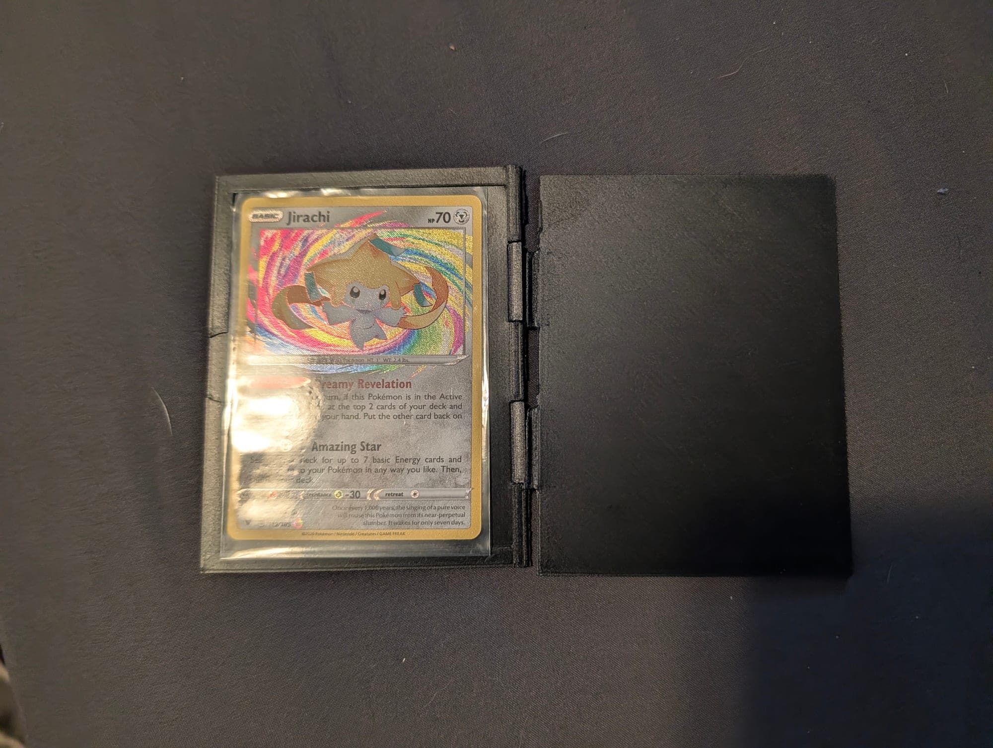 Black card display case open, holding a holographic Pokémon card in a toploader
